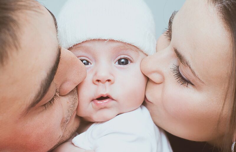 parents kissing their baby